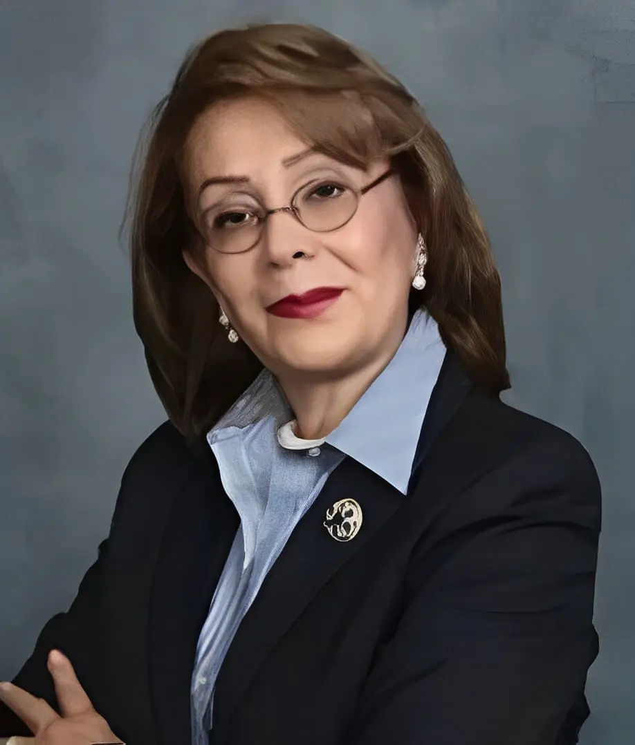 A woman in glasses and a suit poses for the camera.