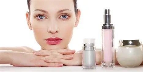 A woman with her hands on her face and two bottles of cosmetics